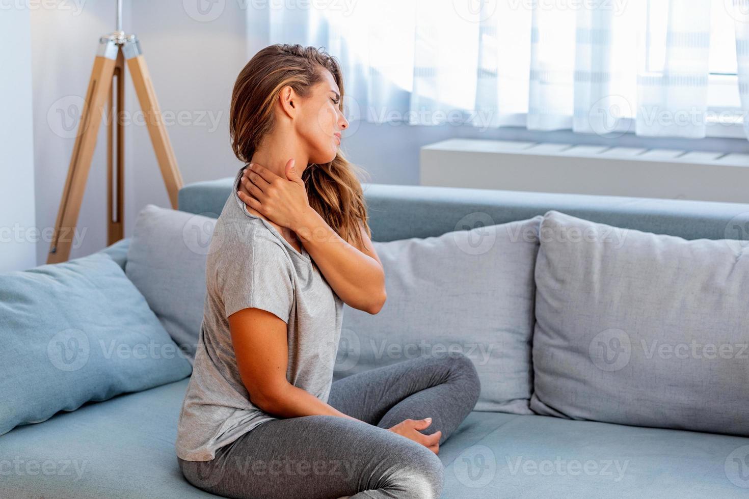 pijn in de schouder. bovenste arm pijn, mensen met lichaamsspieren probleem, gezondheidszorg en geneeskunde concept. aantrekkelijk vrouw zittend Aan de bed en Holding pijnlijk schouder met een ander hand. foto