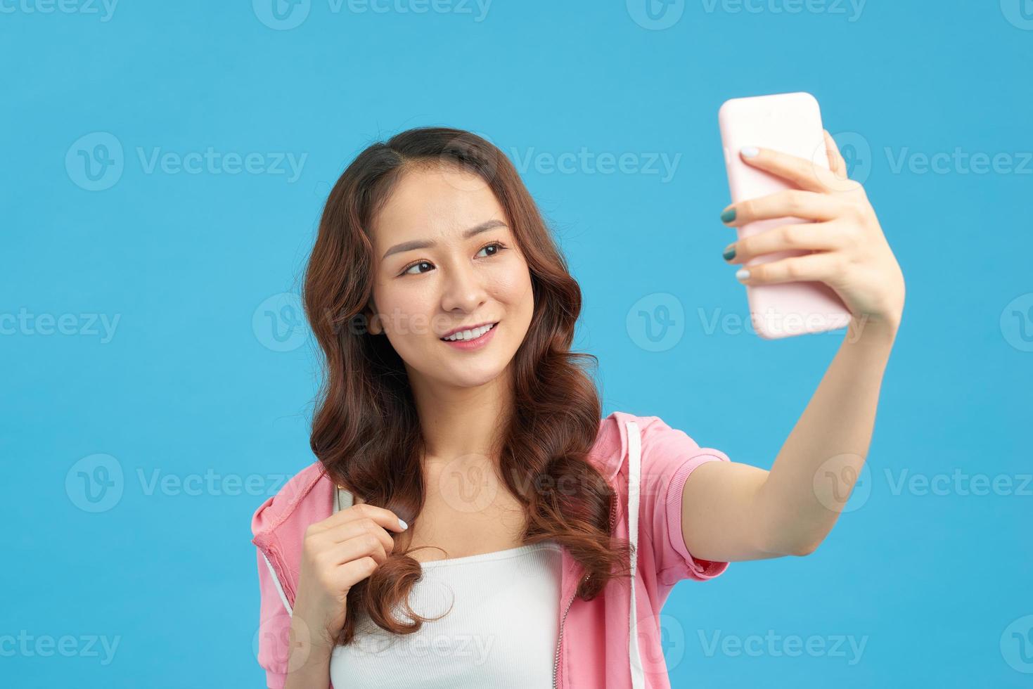 Aziatisch vrouw nemen selfie naar smartphone geïsoleerd Aan blauw achtergrond foto