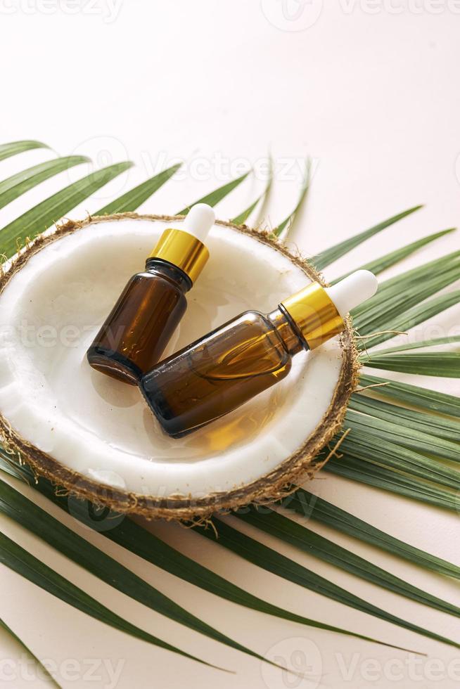 kokosnoot olie in fles met Open noten en pulp in kan, groen palm blad achtergrond. natuurlijk kunstmatig producten. foto