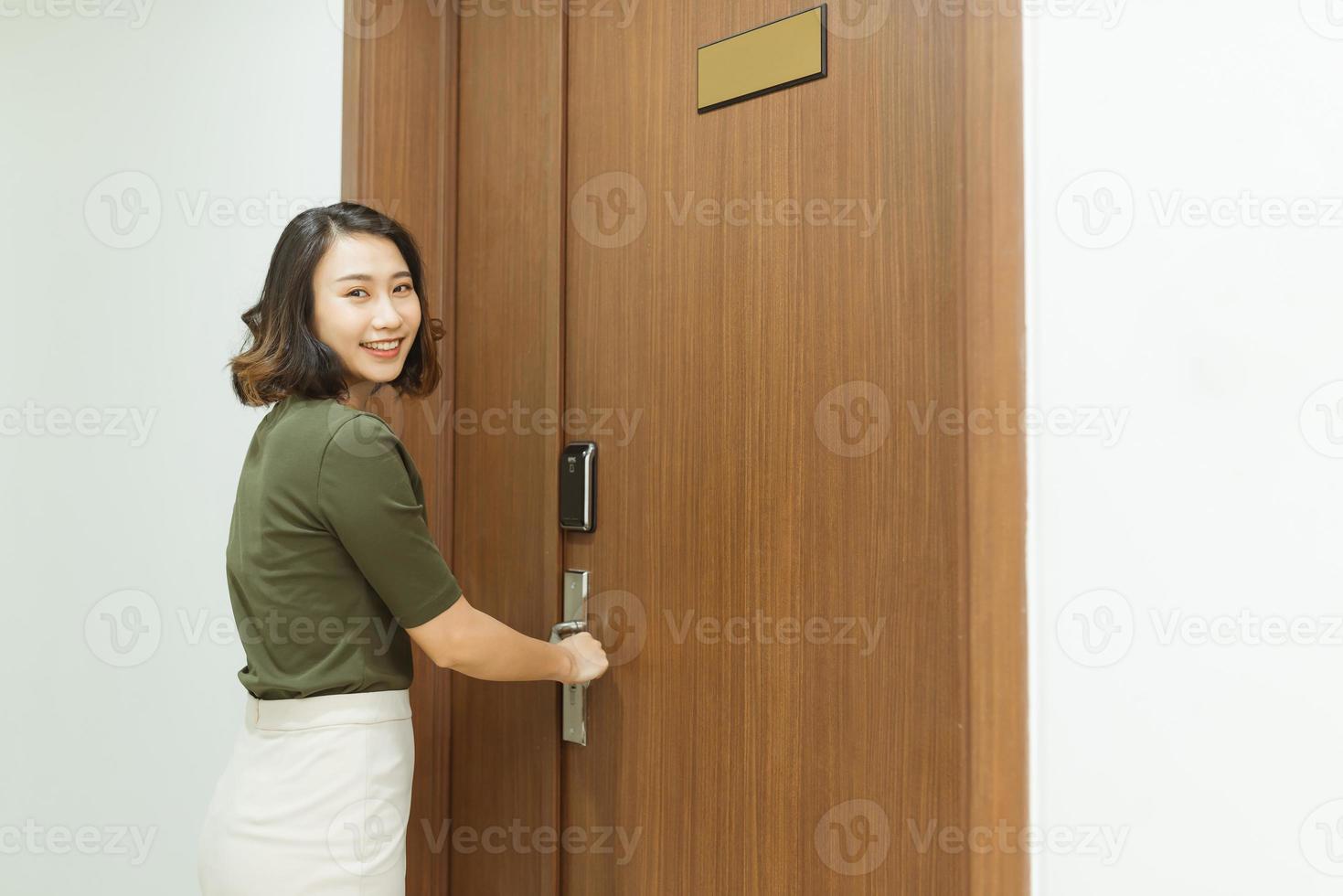 glimlachen aantrekkelijk jong vrouw binnengaan een huis op zoek Bij de camera net zo ze geduwd Open de deur van appartement foto