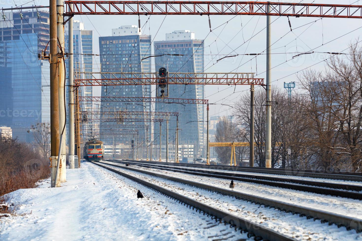 spoorweg multilijn snelweg met een in beweging elektrisch trein tegen de backdrop van een stedelijk winter landschap. foto