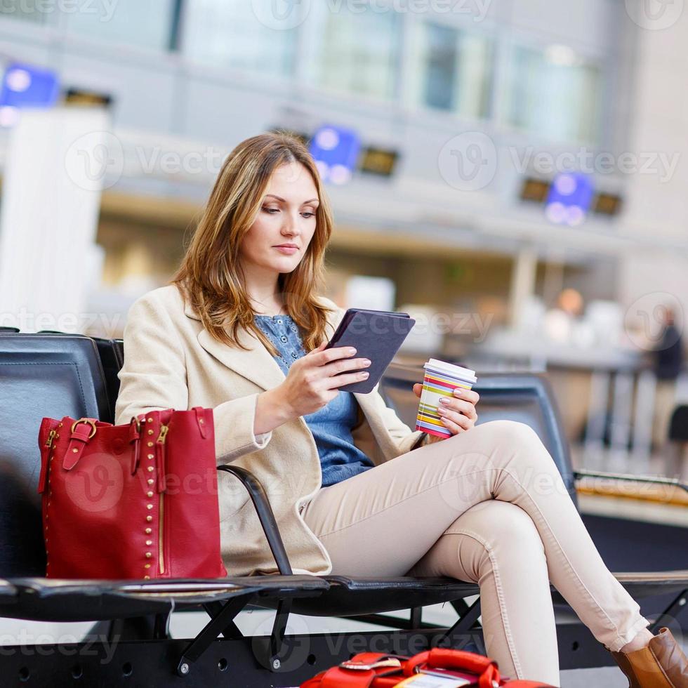 vrouw op de internationale luchthaven, ebook lezen en koffie drinken foto