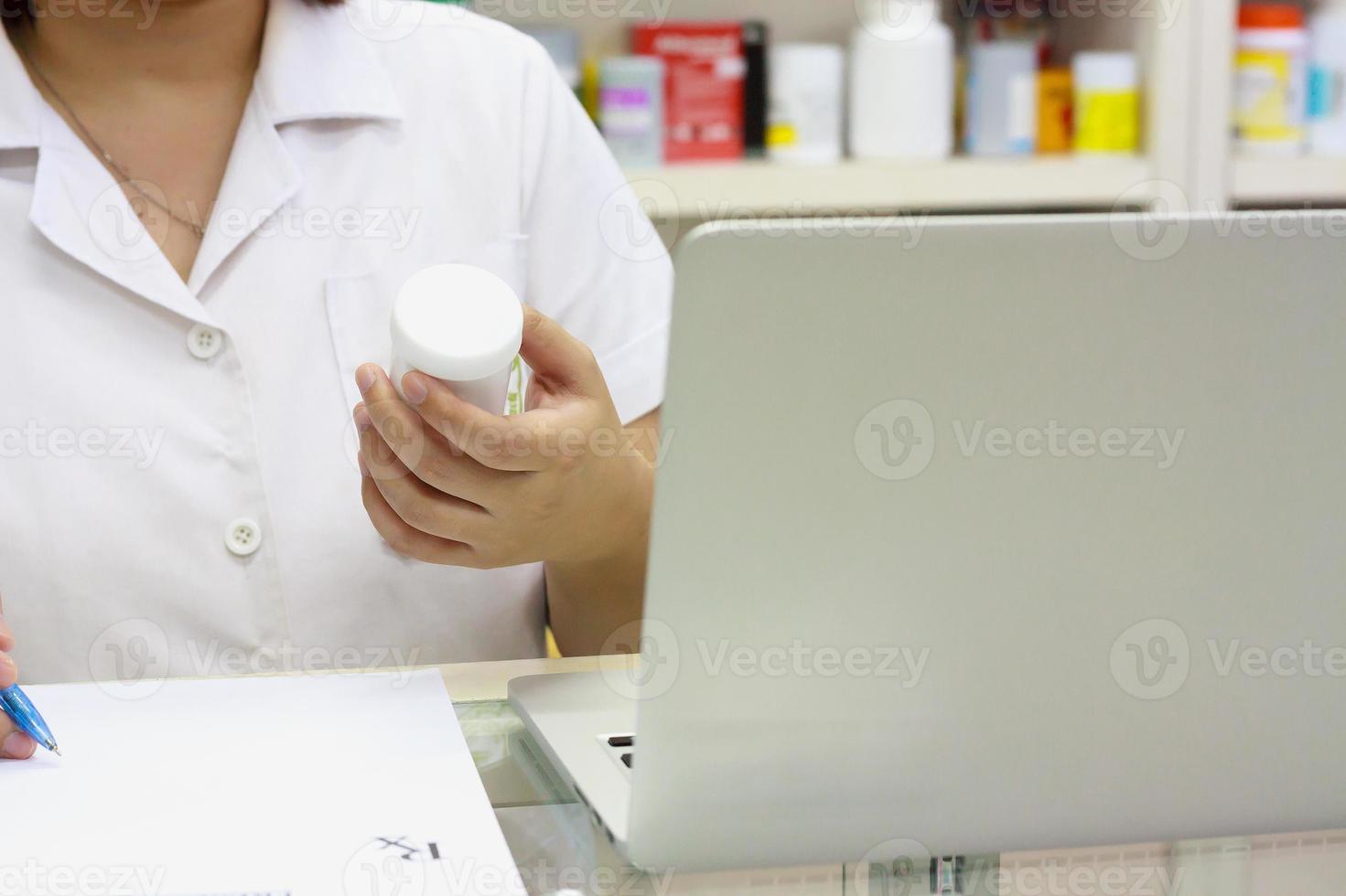 apotheker met laptopcomputer en medicatie in de apotheek foto