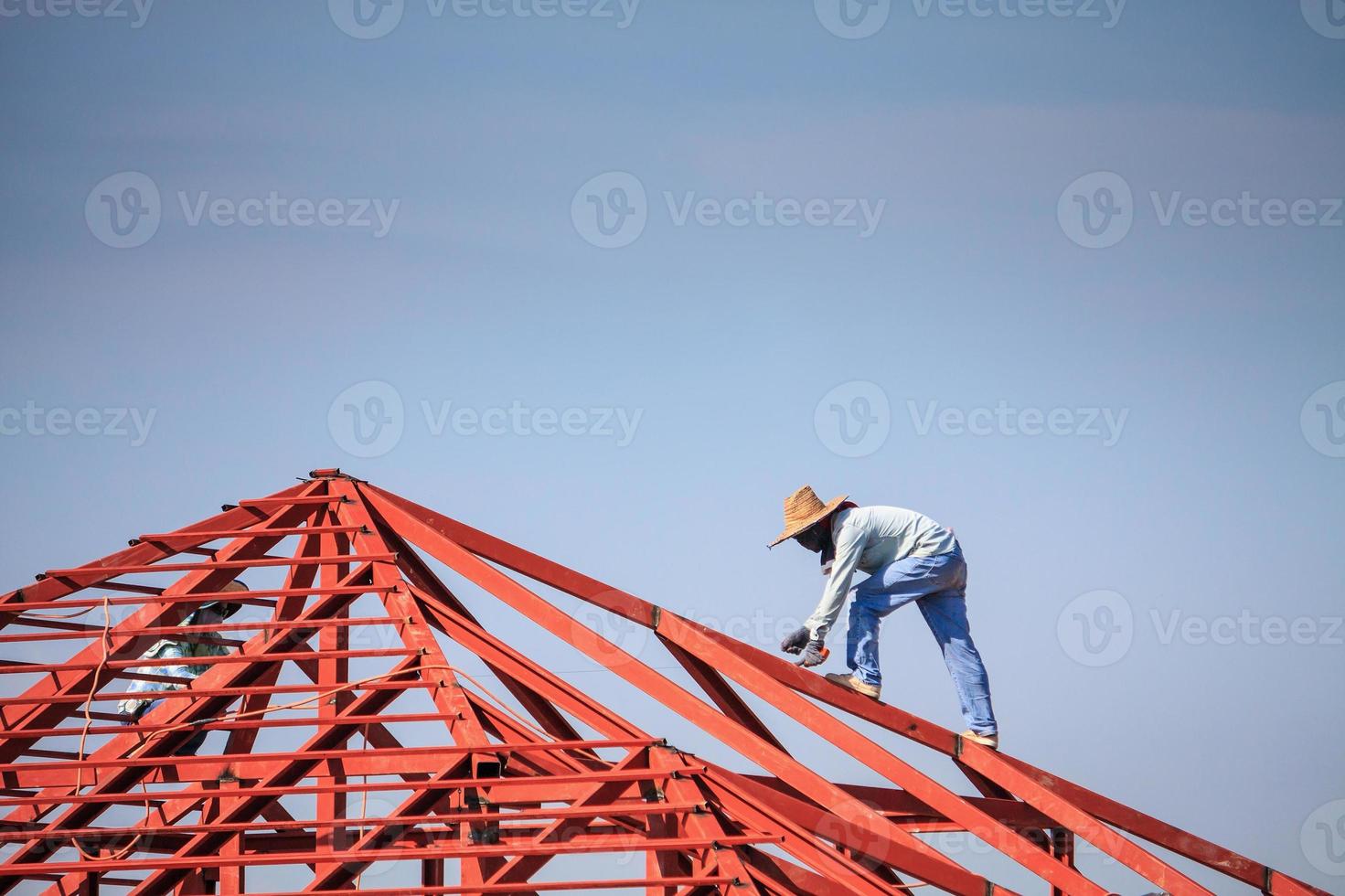 Lassers die stalen framestructuur van het huisdak installeren op de bouwplaats foto