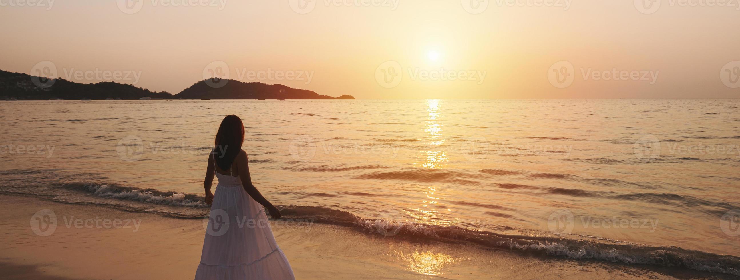 eenzaam jong vrouw wandelen en genieten van mooi zonsondergang Aan de rustig strand, reizen Aan zomer vakantie concept, banier panorama foto