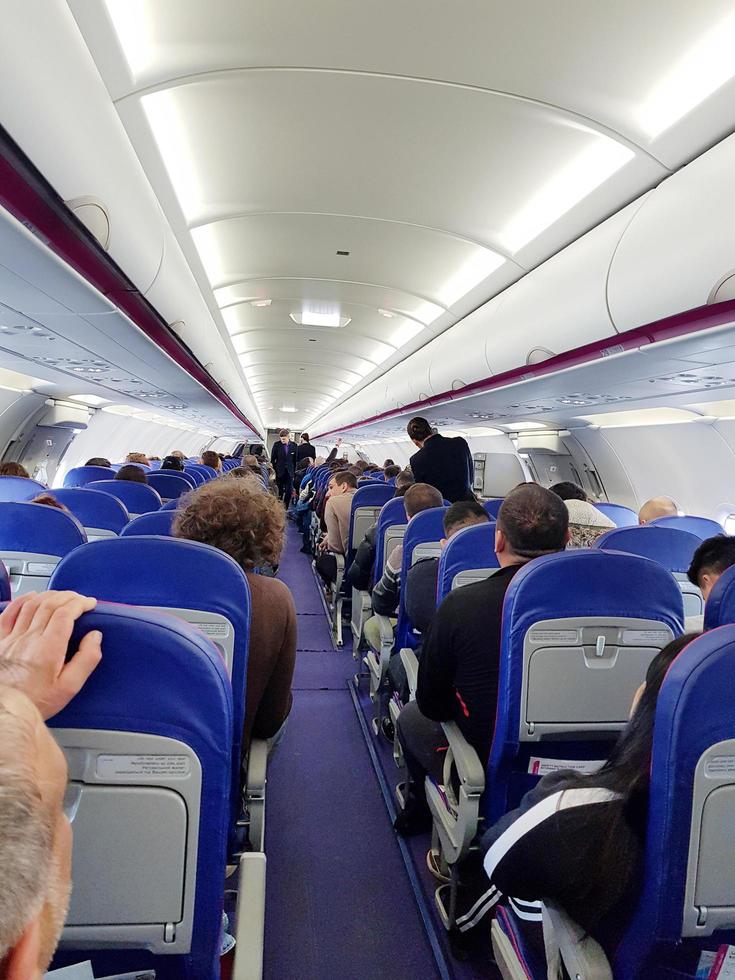 Londen, uk, 2019 - interieur van een vliegtuig met passagiers Aan stoelen aan het wachten naar nemen uit. foto