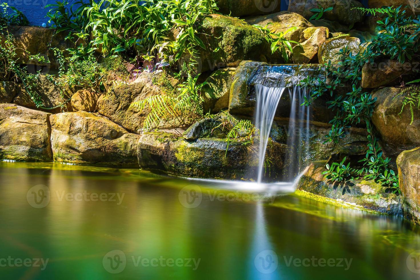 Japans tuin watervallen. weelderig groen tropisch koi vijver met waterval van elk kant. een weelderig groen tuin met waterval trapsgewijs naar beneden de rotsachtig stenen. zen en vredig achtergrond. foto