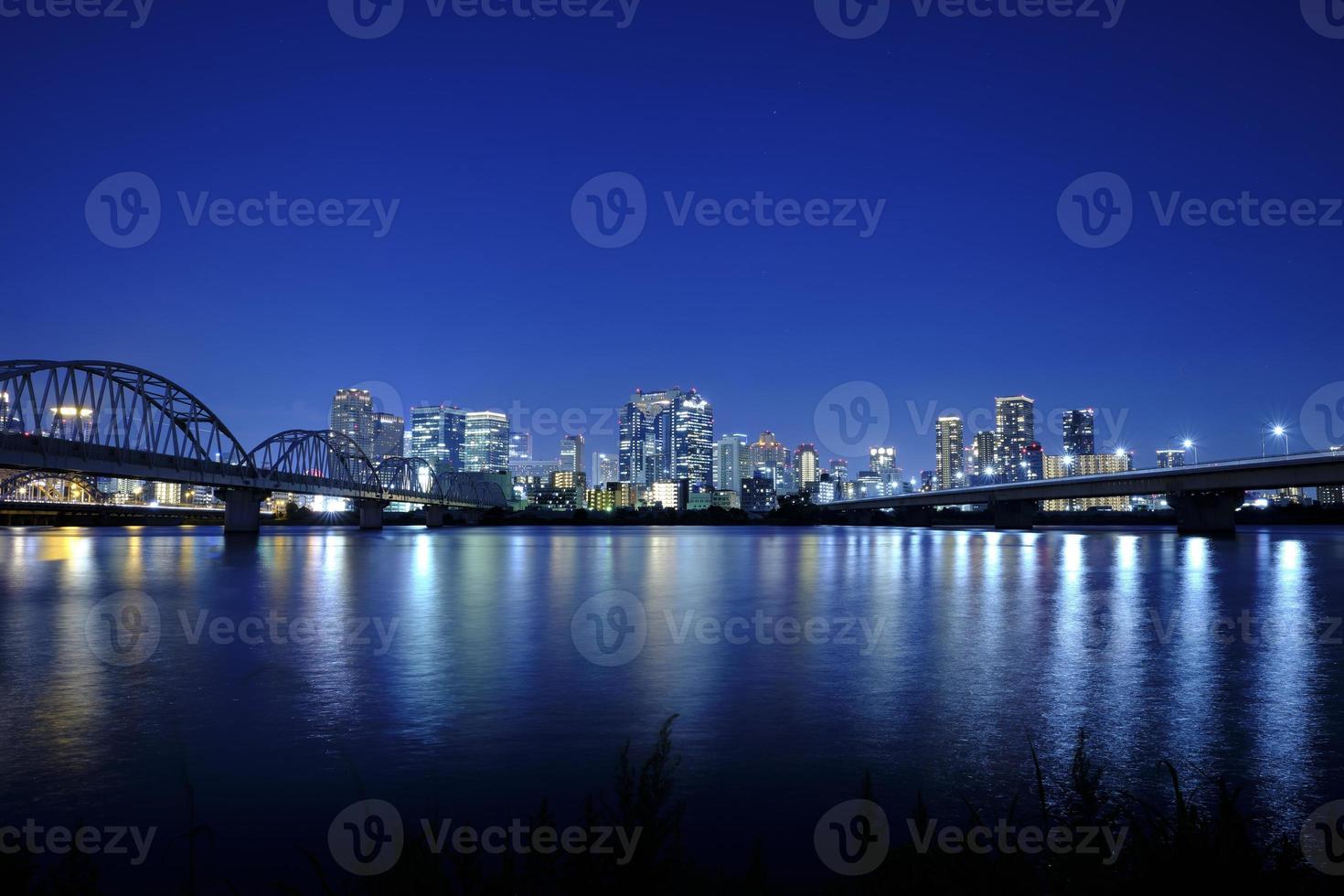 downtown Osaka aan de overkant de jodo rivier- met helder lang blootstelling Bij nacht foto