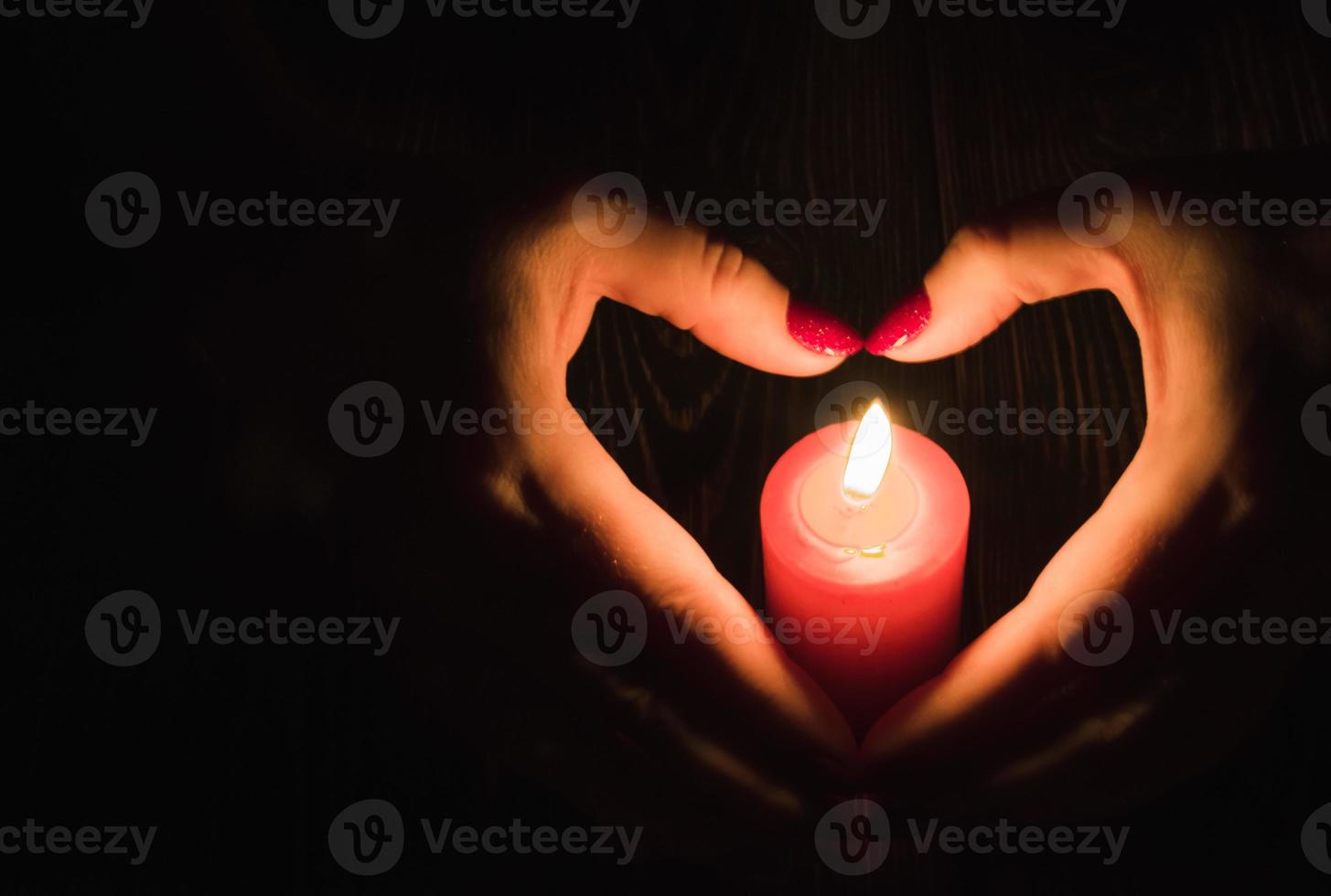 vrouw handen Holding een brandend kaars in de donker, hart shpe foto