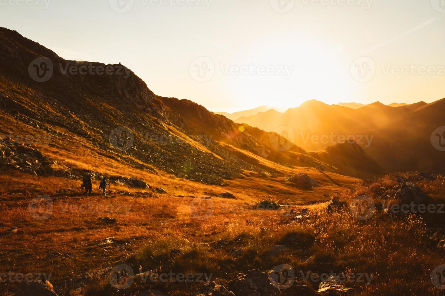 Mens en vrouw wandelaars in afstand wandeltocht Aan spoor buitenshuis Aan mooi zonsondergang in herfst samen tegen zon. filmische inspirerend actief mensen Aan trektocht in Kaukasus bergen foto