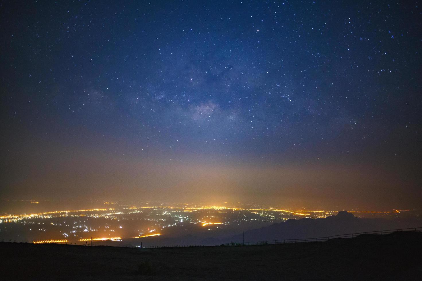 melkwegstelsel en stadslicht bij phetchabun in phetchabun in thailand.lange belichtingsfoto.met graan foto