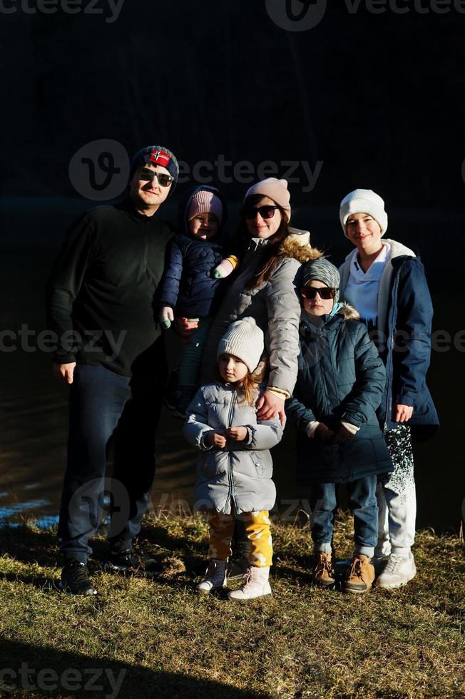 groot familie met vier kinderen in pond Bij vroeg voorjaar park. foto