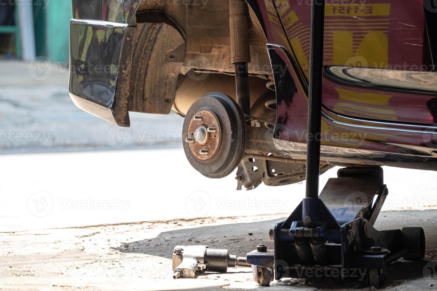 de auto jack is hijs- de auto dikker worden. terwijl de monteur verwijdert de band voor reparatie repareren banden in de garage, auto assen foto