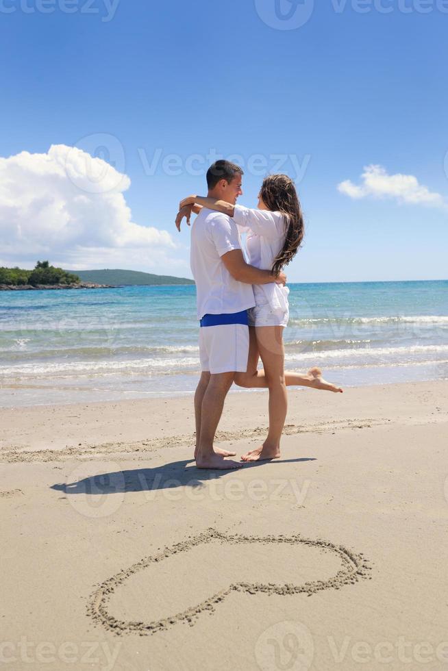 romantisch paar in liefde hebben pret Aan de strand met hart tekening Aan zand foto