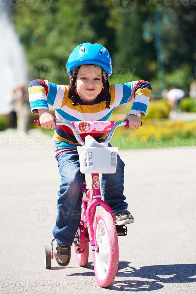 gelukkig jongen aan het leren naar rijden zijn eerste fiets foto