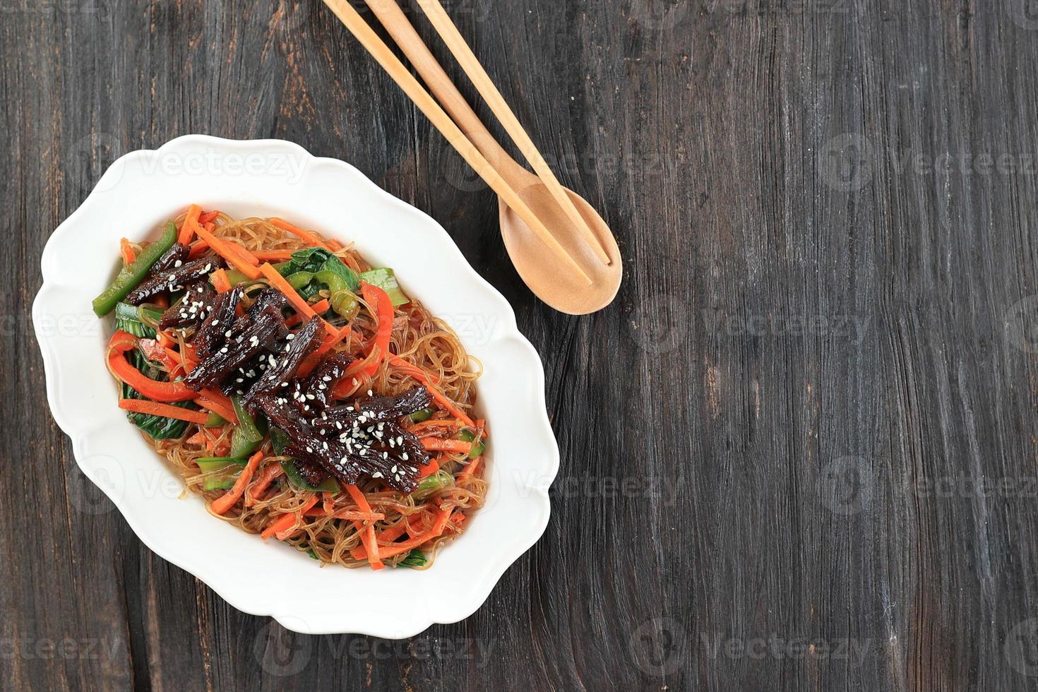 japchae, glas noedels roeren gebakken met groenten en rundvlees, geserveerd Aan wit bord. Koreaans authentiek keuken foto