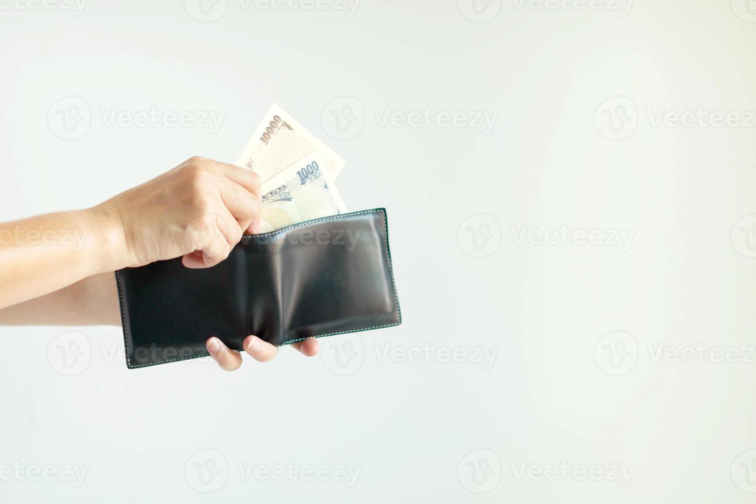 een hand- is plukken Japan papier geld in de valuta van yen of Japanse Yen, van de kort portemonnee voor betaling. foto