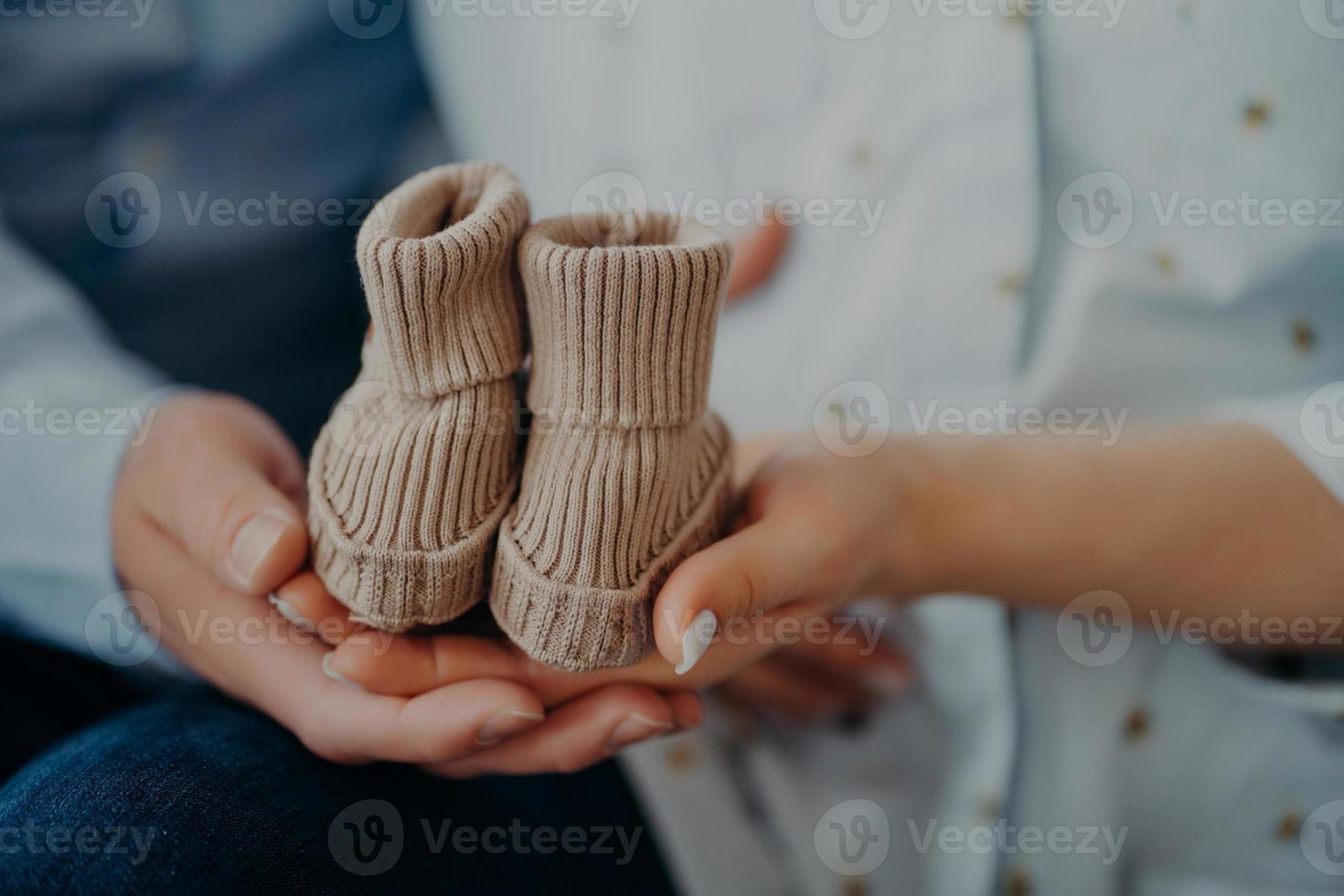 bijgesneden schot van toekomst ouders anticiperen voor kind houden baby laarzen tonen klein schoenen voor komt eraan baby. ouderschap zwangerschap geboorte liefde en familie concept. foto