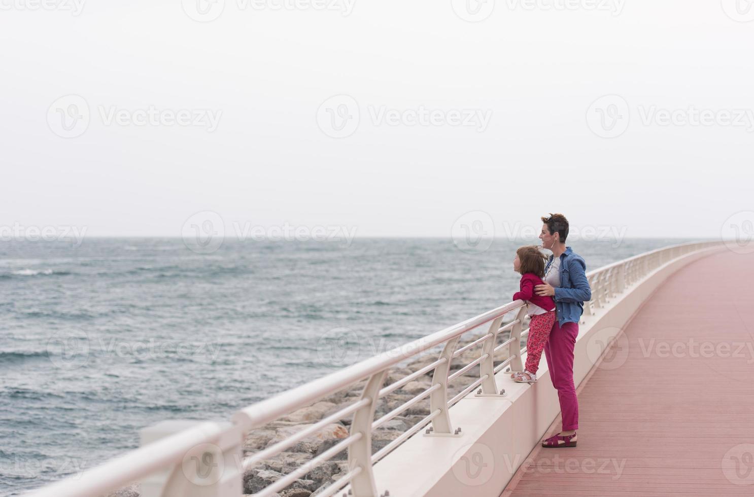 moeder en schattig weinig meisje Aan de promenade door de zee foto