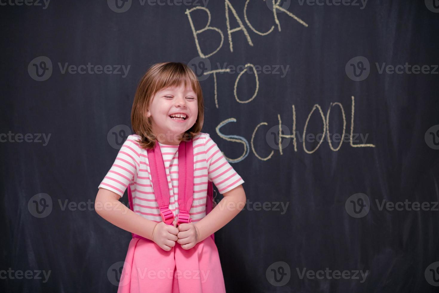 school- meisje kind met rugzak schrijven schoolbord foto