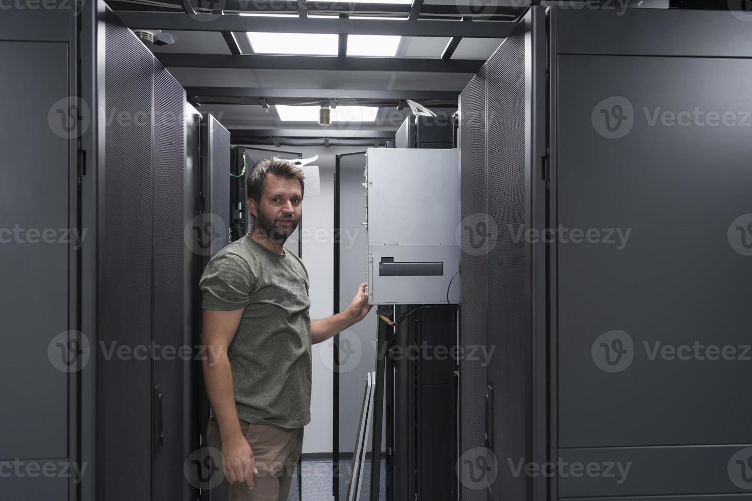 het ingenieur werken in de server kamer of gegevens centrum de technicus zet in een rek een nieuw server van zakelijke bedrijf mainframe supercomputer of cryptogeld mijnbouw boerderij. foto