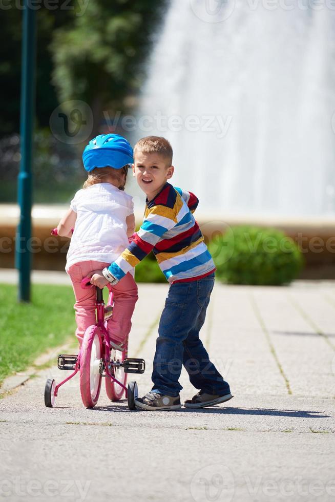 jongen en meisje in park aan het leren naar rijden een fiets foto