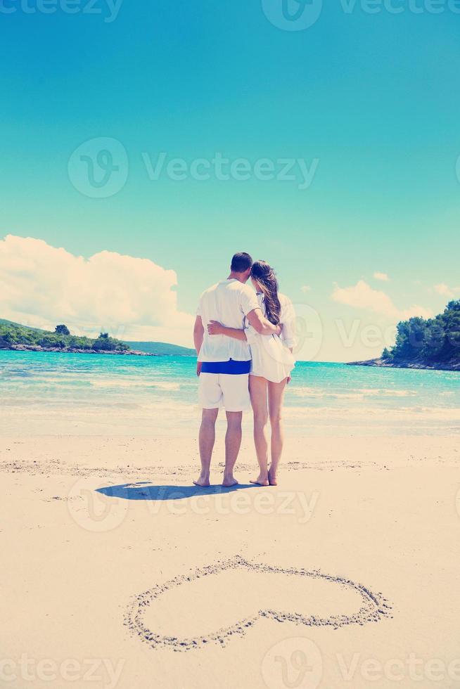 romantisch paar in liefde hebben pret Aan de strand met hart tekening Aan zand foto