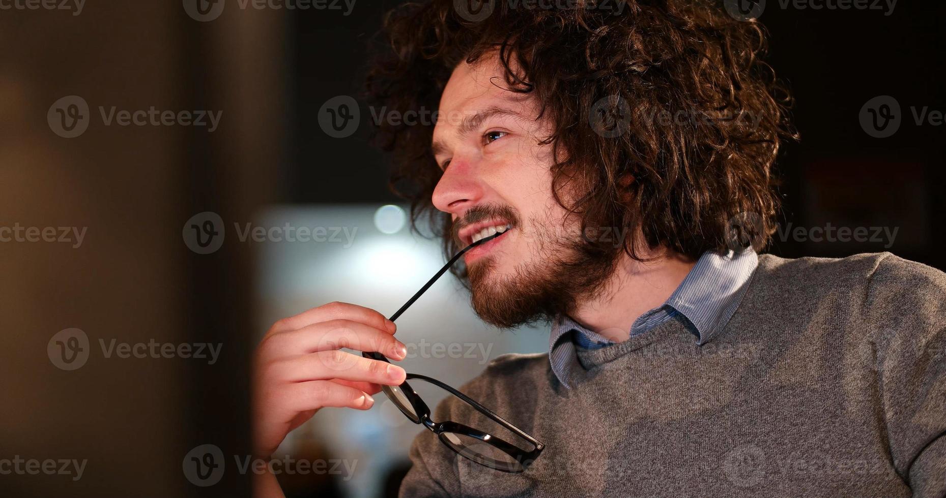 Mens werken Aan computer in donker kantoor foto