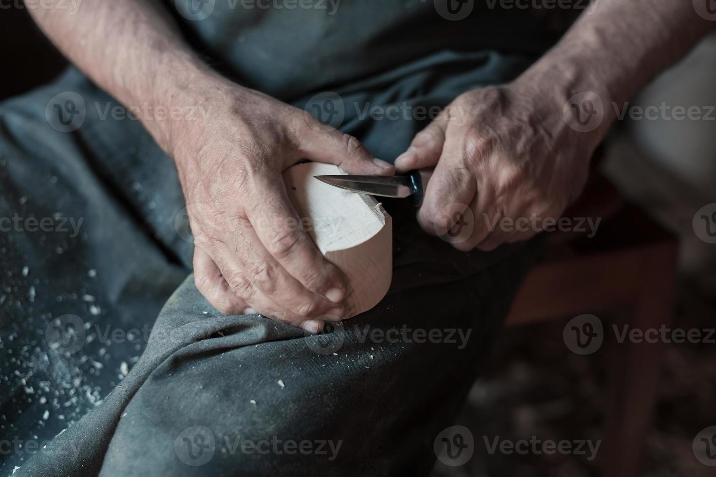 handen snijwerk kop van hout, werken met beitel dichtbij omhoog. houten werkplaats. werkwijze van maken houten keukengerei foto