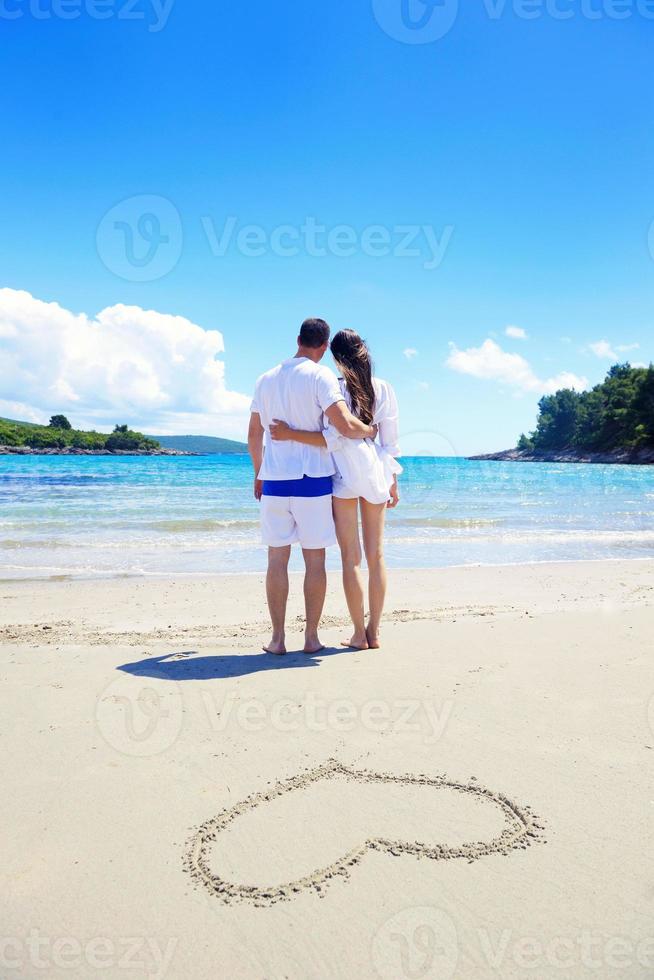 romantisch paar in liefde hebben pret Aan de strand met hart tekening Aan zand foto