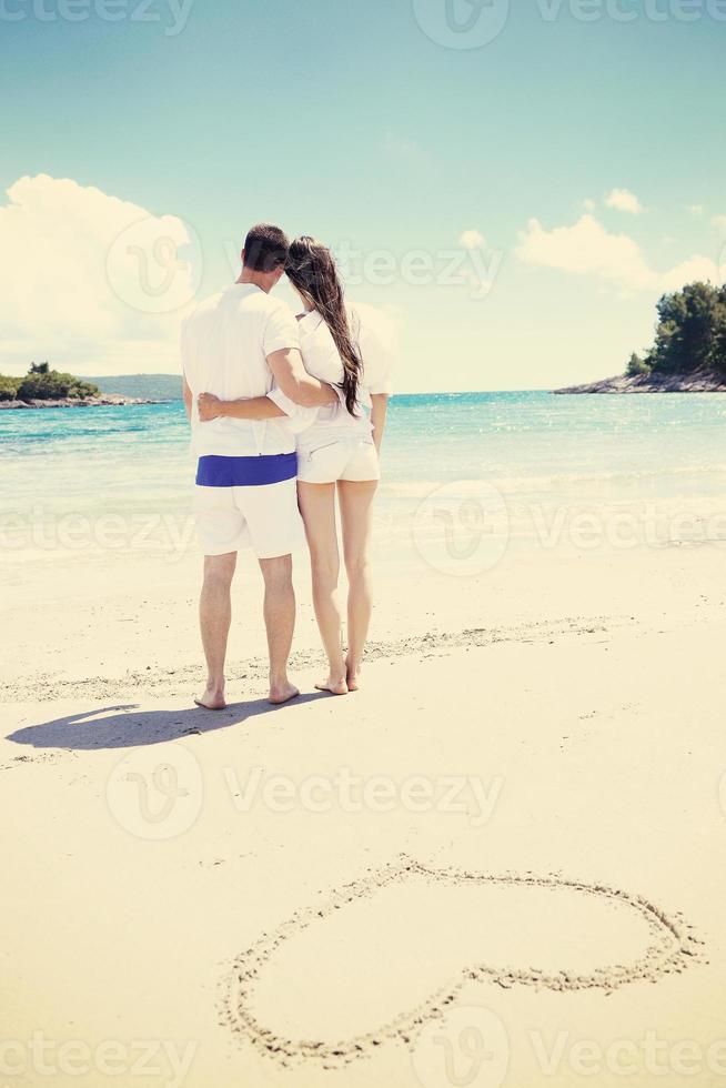 romantisch paar in liefde hebben pret Aan de strand met hart tekening Aan zand foto