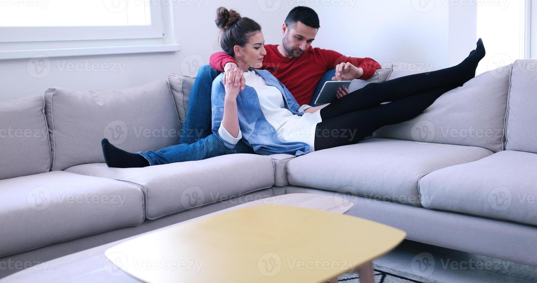 paar ontspannen thuis met tabletcomputers foto