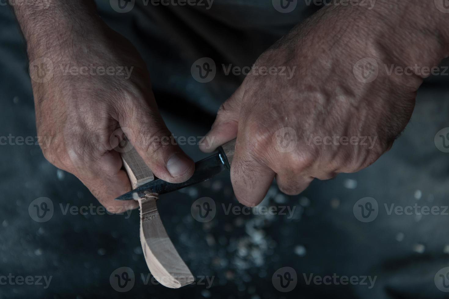 handen snijwerk lepel van hout, werken met beitel dichtbij omhoog. houten werkplaats. werkwijze van maken houten lepel foto