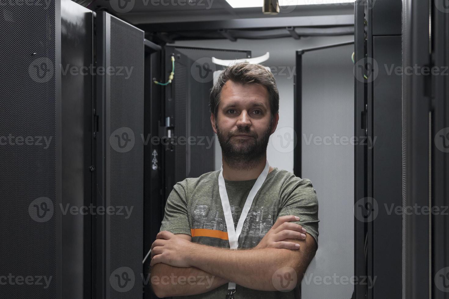 portret van mannetje technicus of netwerk beheerder staand dapper net zo een held met armen gekruiste in gegevens centrum server kamer. foto