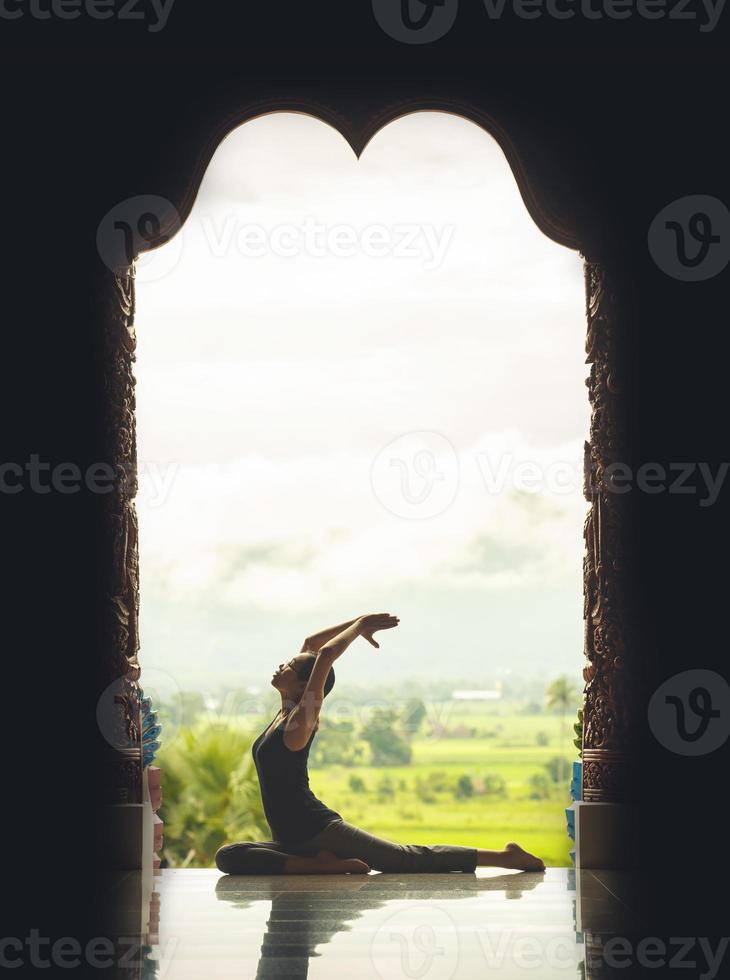 silhouet jong vrouw beoefenen yoga Aan de tempel Bij zonsondergang - wijnoogst stijl kleur effect foto