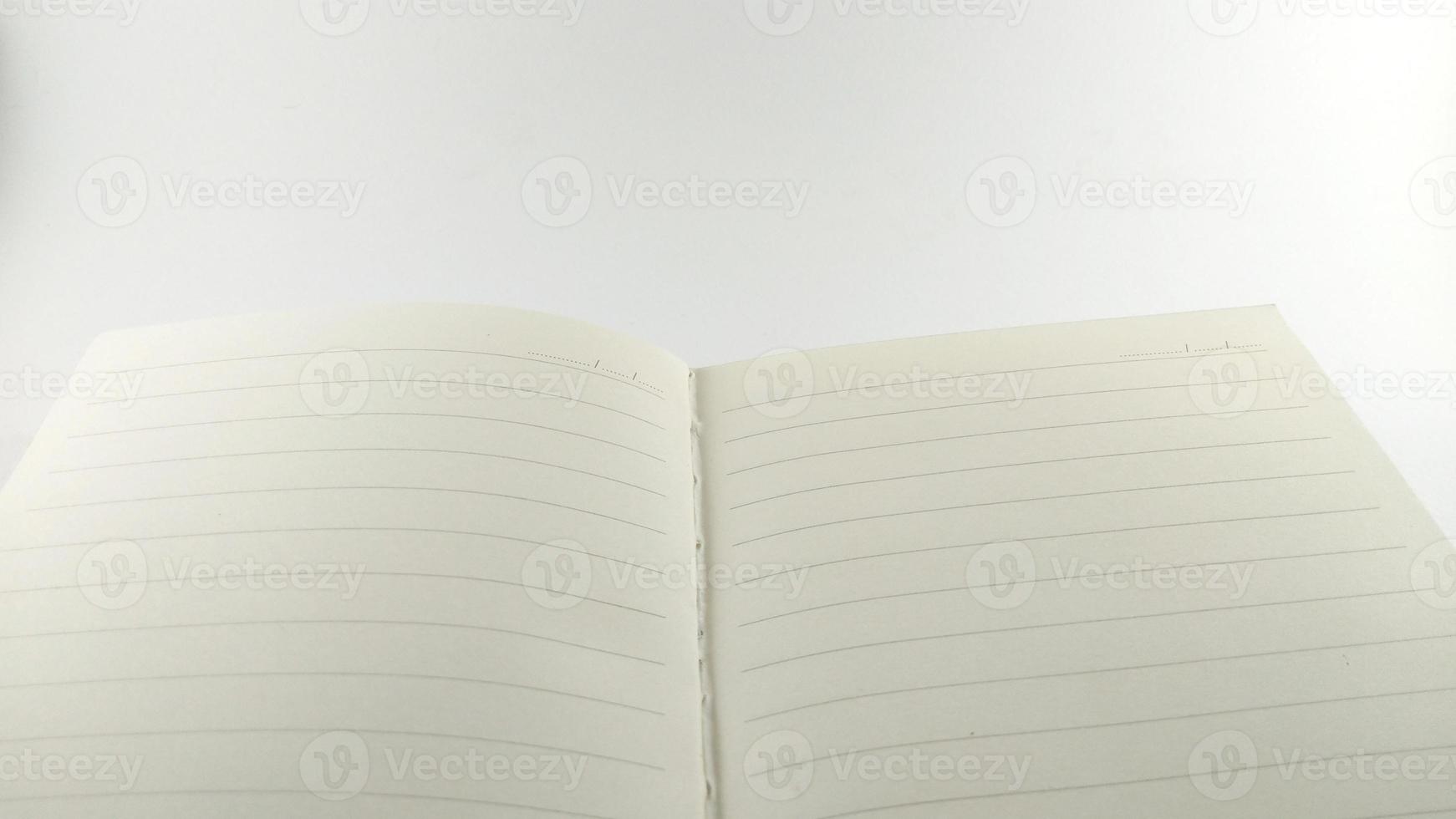 een romig wit notitieboekje verspreiding uit in de centrum en geplaatst Aan een wit tafel. foto