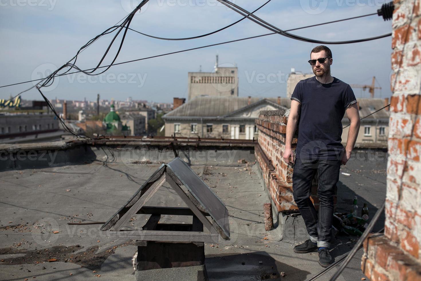 de man in de authentieke zelfkant van laarzen en jeans op het dak van het gebouw in de oude stad foto