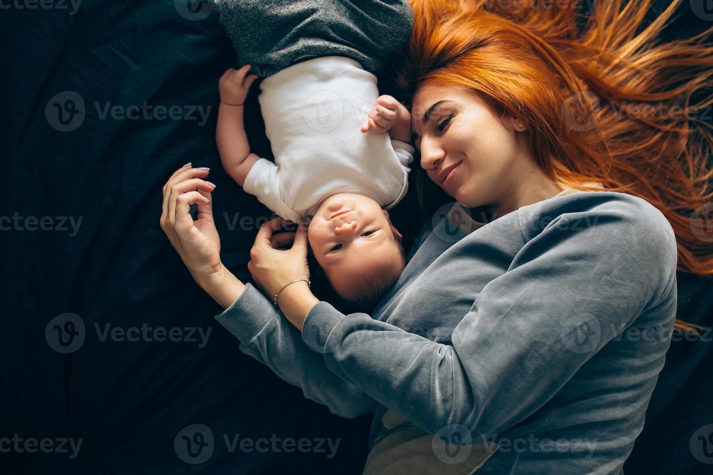 gelukkig moeder met baby aan het liegen samen Aan bed foto