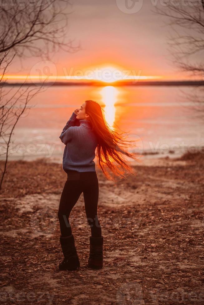 vrouw genieten van tijd ontspannende door de mooi meer Bij zonsopkomst. foto