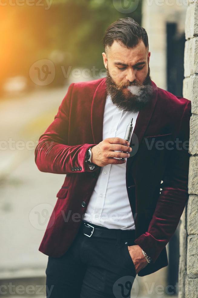 rijke man met een baard rookt elektronische sigaret foto