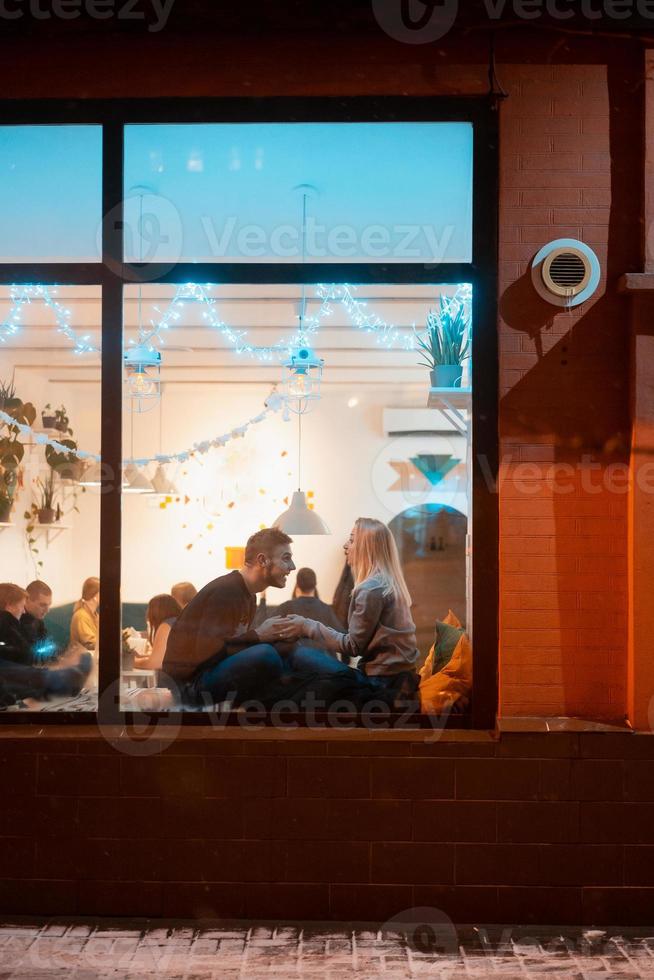 foto door venster. jong paar in cafe met elegant interieur