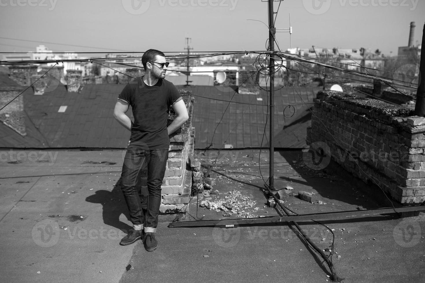 de man in de authentieke zelfkant van laarzen en jeans op het dak van het gebouw in de oude stad foto