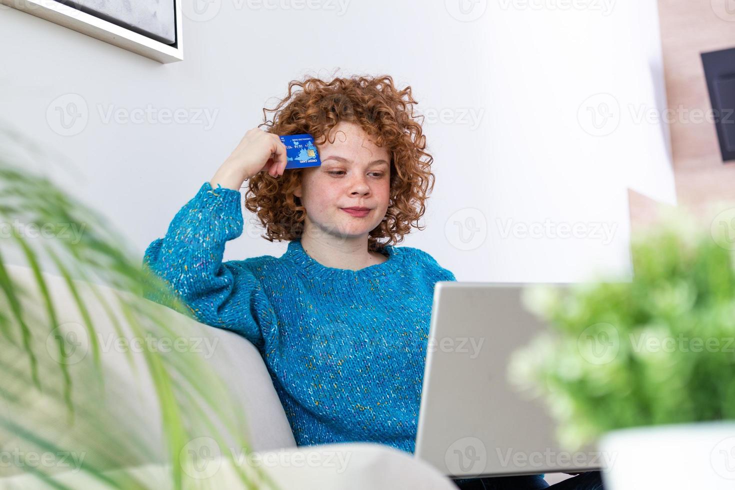 schattig rood haar- vrouw boodschappen doen online met credit kaart. vrouw Holding credit kaart en gebruik makend van laptop. online boodschappen doen concept foto