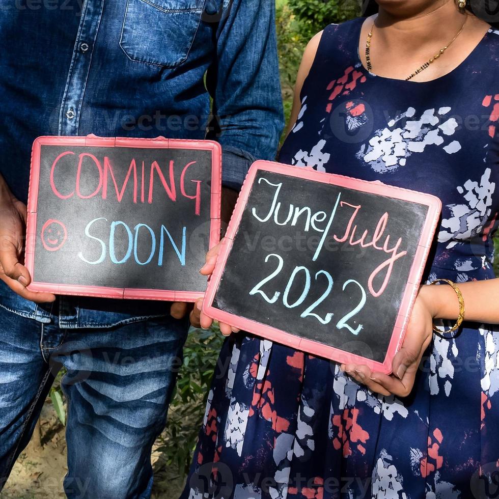 indiase paar poseren voor zwangerschaps baby shoot. het paar poseert in een gazon met groen gras en de vrouw pronkt met haar babybuil in de Lodhi-tuin in New Delhi, India foto