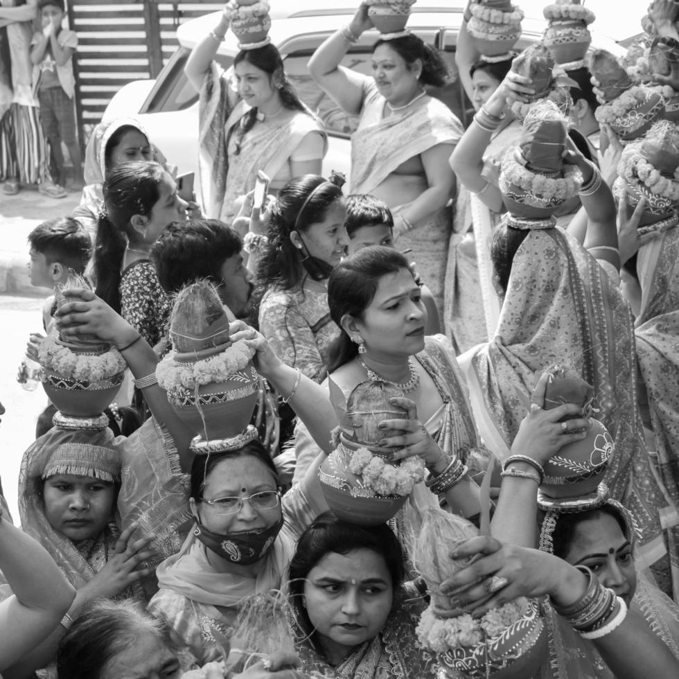 Delhi, Indië april 03 2022 - Dames met kalash Aan hoofd gedurende jagannath tempel mangal kalash jatra, Indisch Hindoe toegewijden dragen aarden potten met heilig water met kokosnoot Aan top-zwart en wit foto