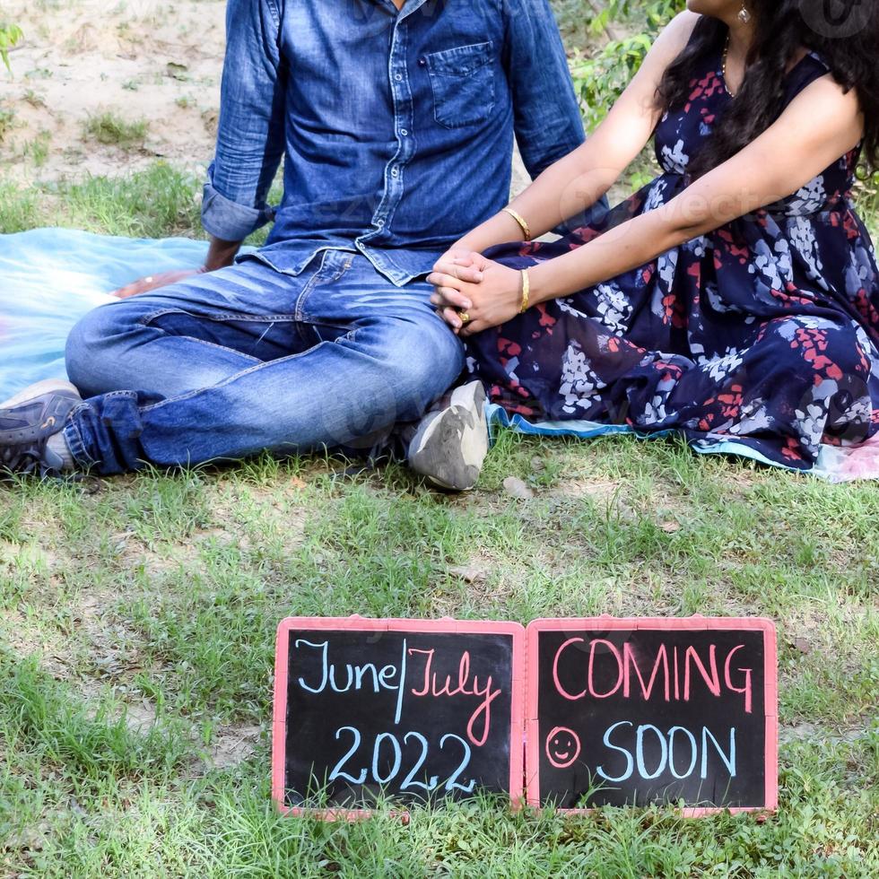 indiase paar poseren voor zwangerschaps baby shoot. het paar poseert in een gazon met groen gras en de vrouw pronkt met haar babybuil in de Lodhi-tuin in New Delhi, India foto