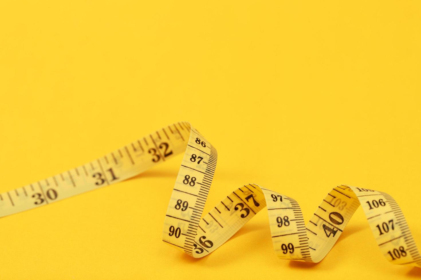 plakband meten voor zwaarlijvig mensen Aan een geel achtergrond zacht focus foto