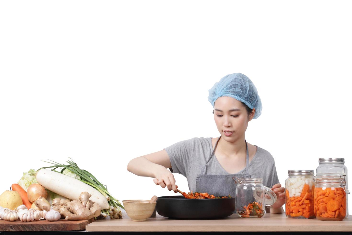 Aziatisch vrouw zittend en maken Kimchi ze is vervelend beschermend handschoenen en een hoed. naar houden voedsel schoon. wit achtergrond Koreaans gefermenteerd voedsel concept gemaakt van groenten. knipsel pad. geïsoleerd foto