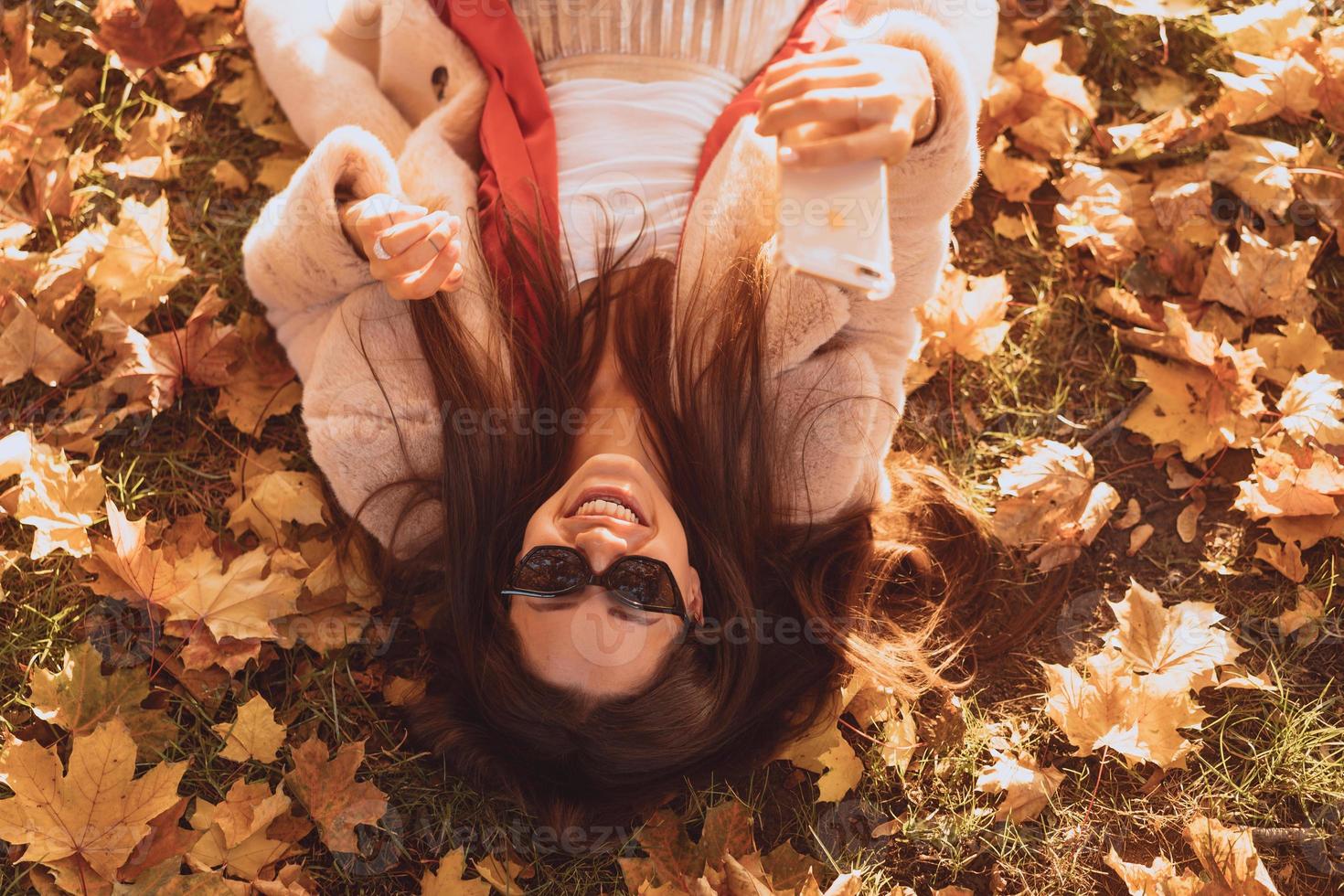 top visie van mooi jong vrouw leugens Aan herfst bladeren foto