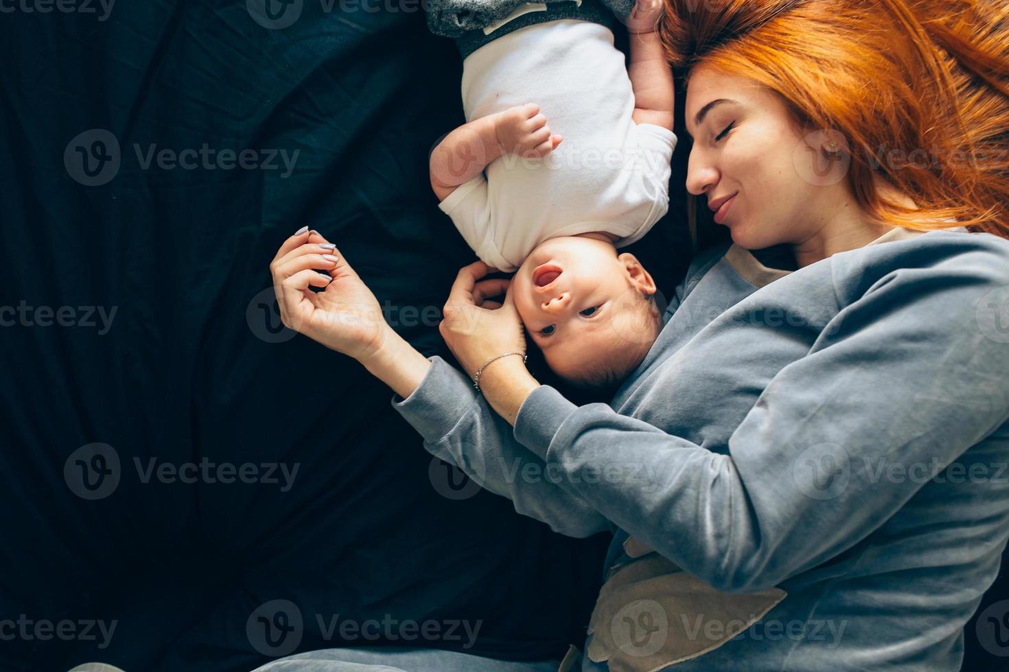 gelukkig moeder met baby aan het liegen samen Aan bed foto